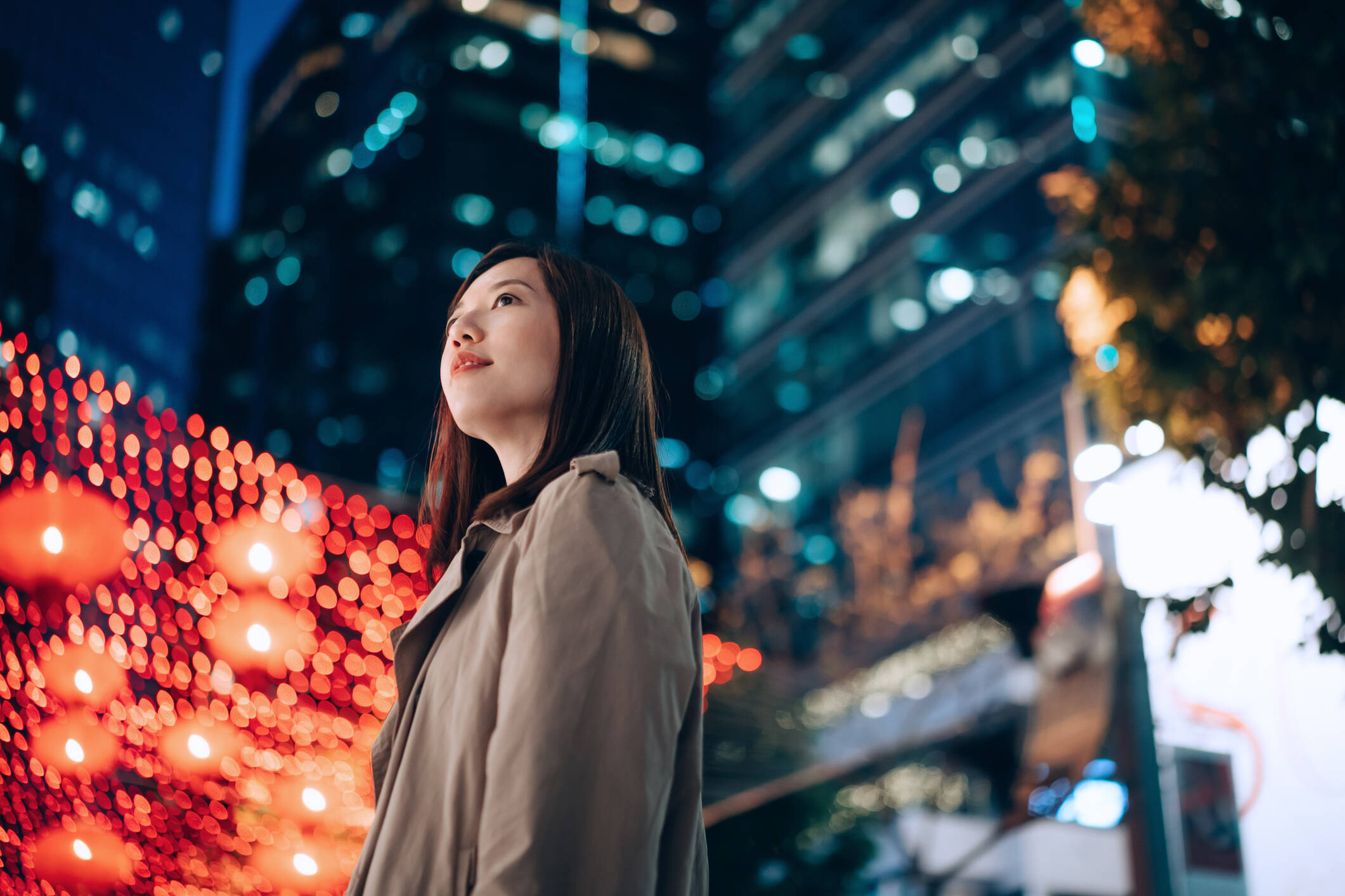 Asian woman in front of city lights at night. 